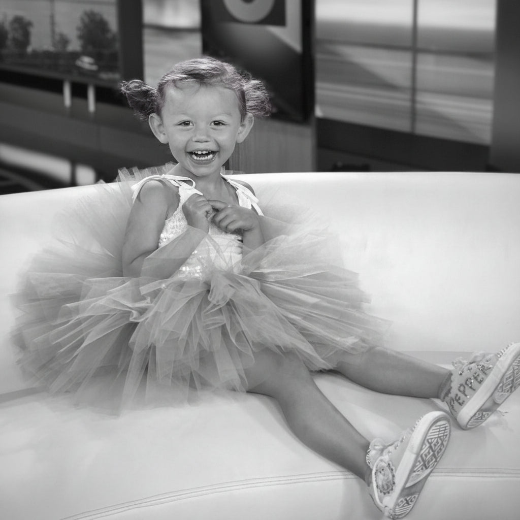 Child in a pink tutu dress sitting on a couch with a blurred background